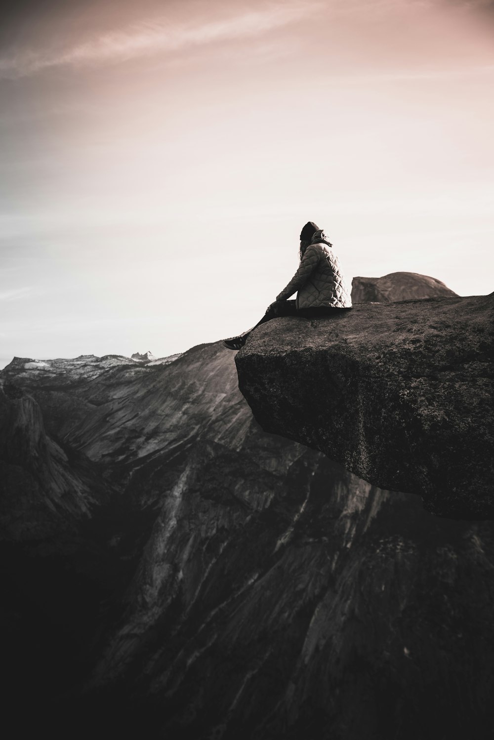 person sitting on cliff during daytime