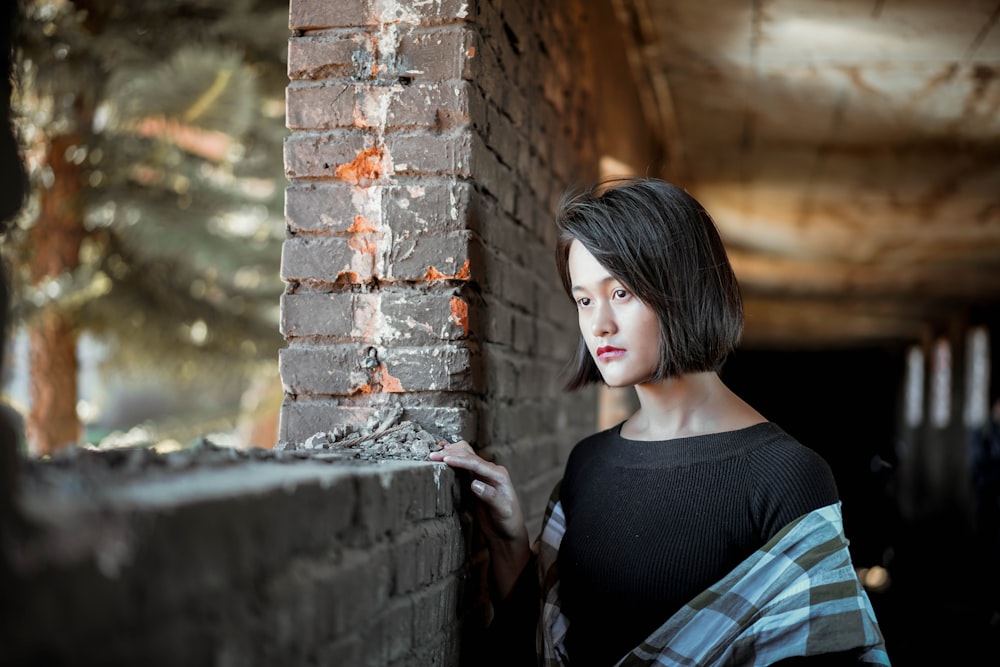 woman standing beside gray brickwall