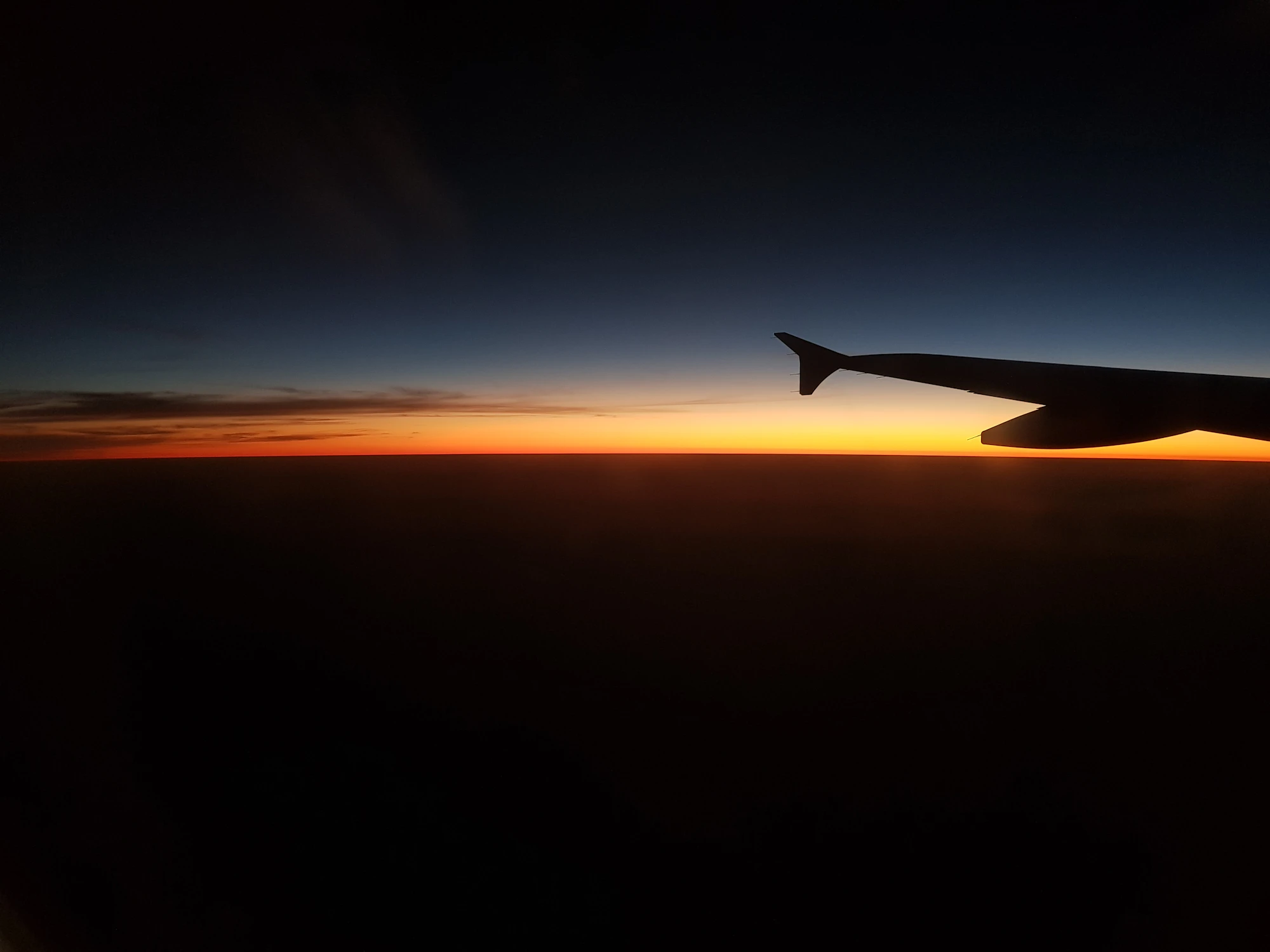 Silhouette of an airplane wing at golden hour
