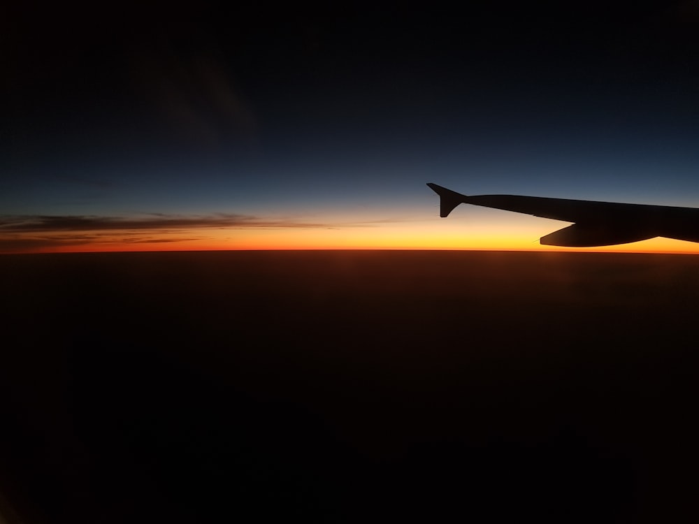 silhouette photograph of plane wing during golden hour