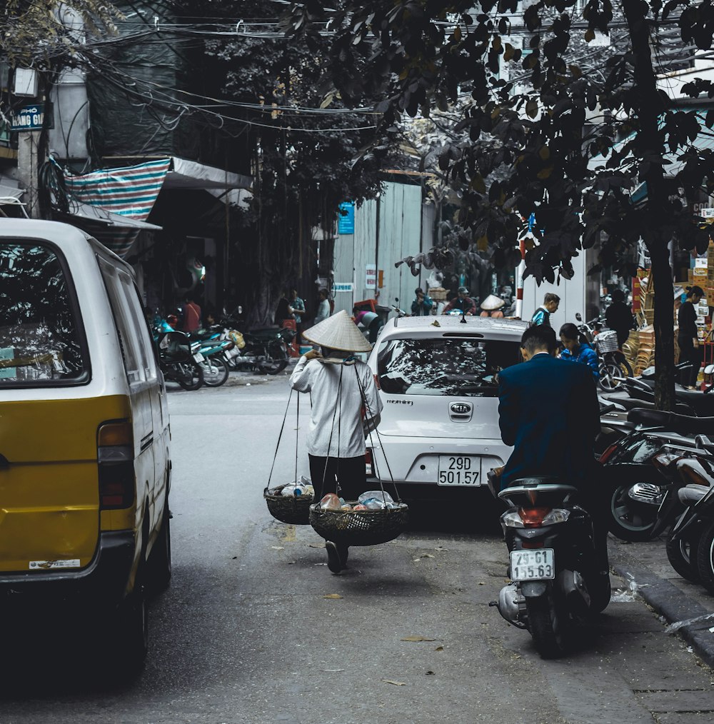 man carrying two baskets using stick walking on road