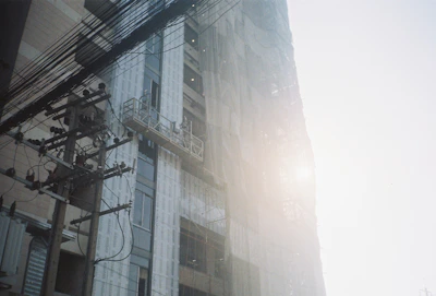 A sturdy scaffolding structure surrounding a high-rise building under construction, bathed in warm sunlight.