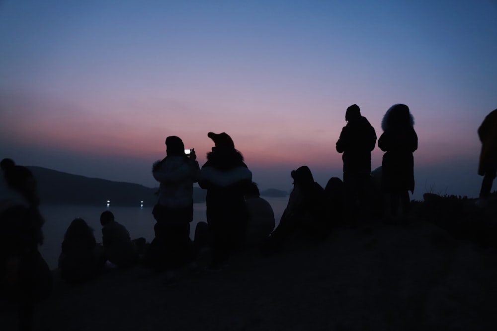 silhouette of people near body of water