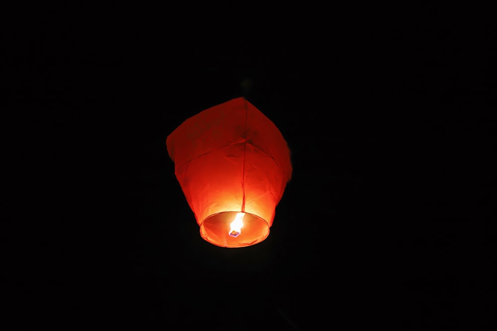 paper lantern with lighted candle in dark room