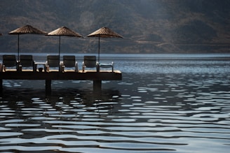 A serene green area with lounge chairs and a picturesque lake in the background.