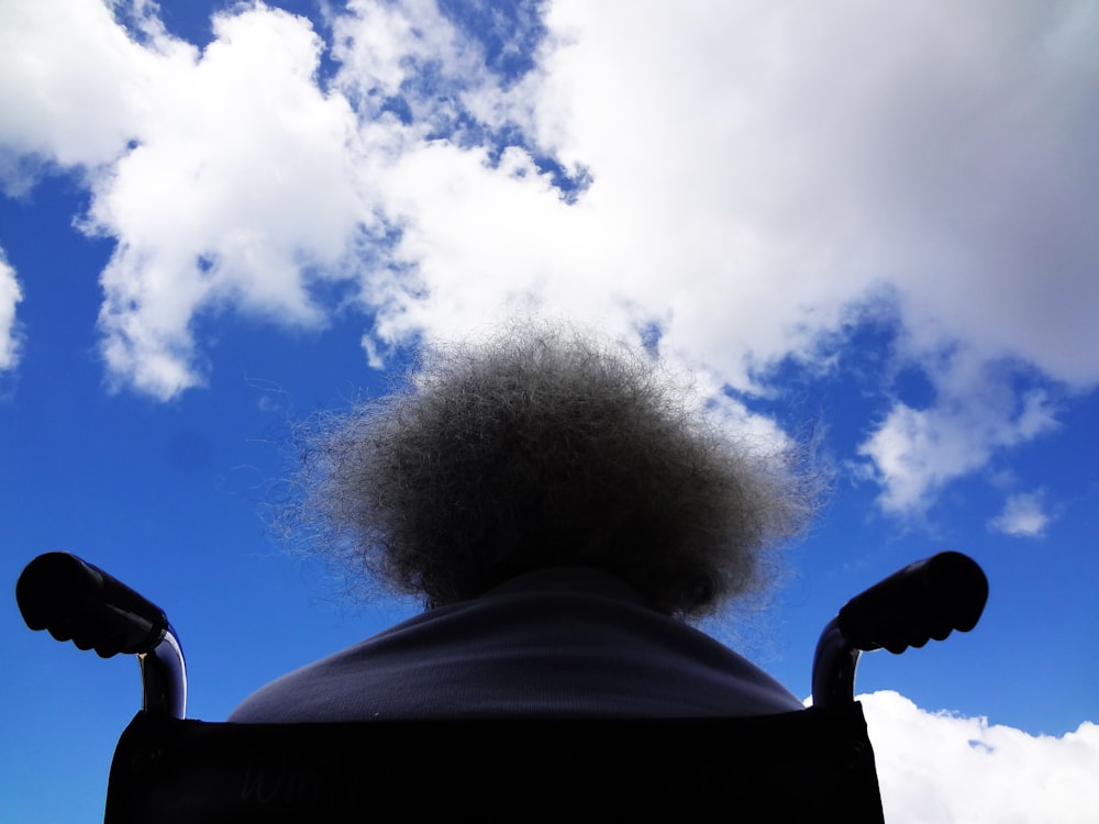 person sitting on black wheelchair staring in the sky