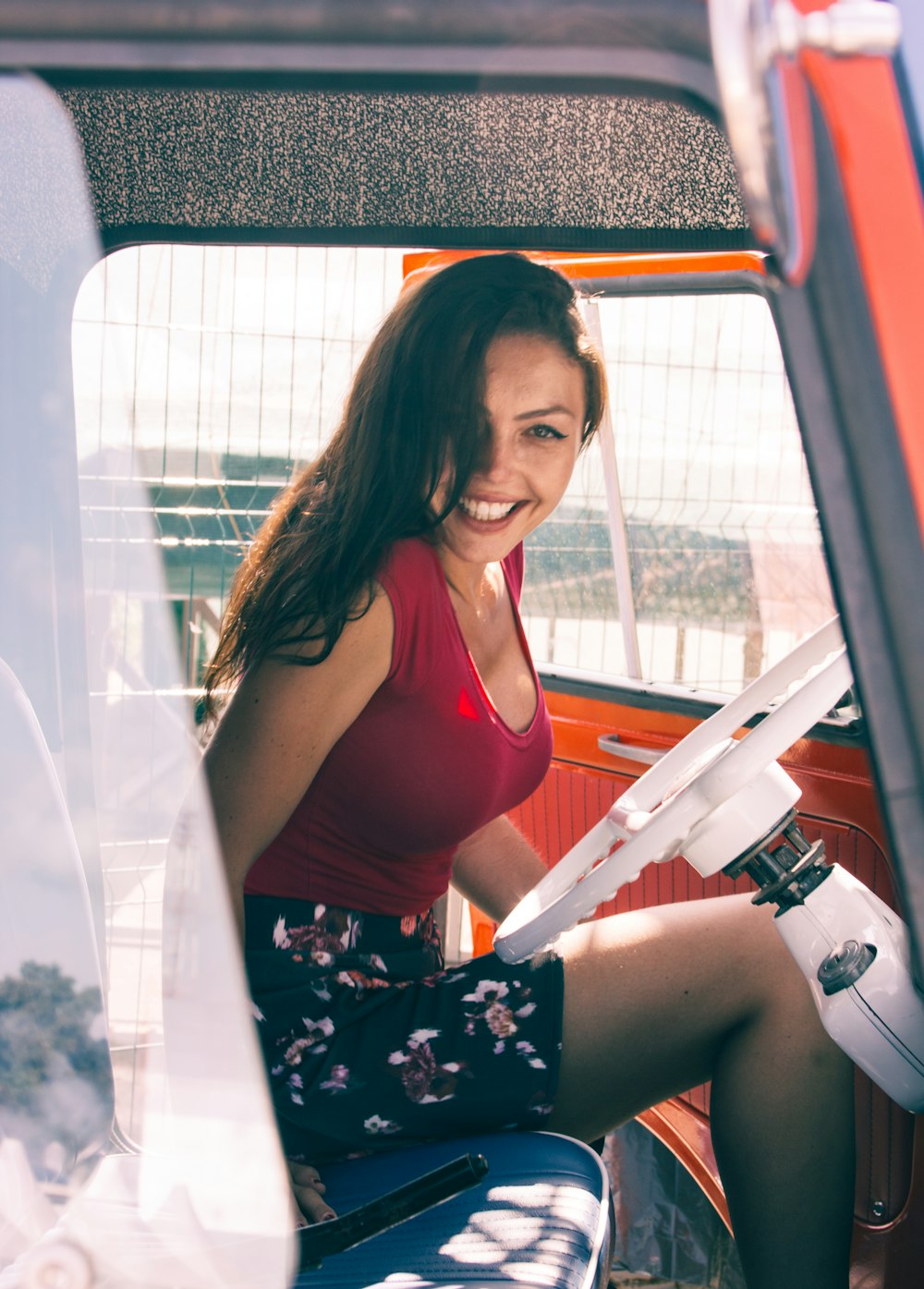 赤いタンクトップと色とりどりの花柄のスカートを着た女性が車内に座っている