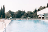 Swimming pool area surrounded by greenery and comfortable lounge chairs.