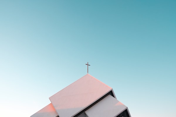 A picture of the rooftop of a church with the cross of Christ on top