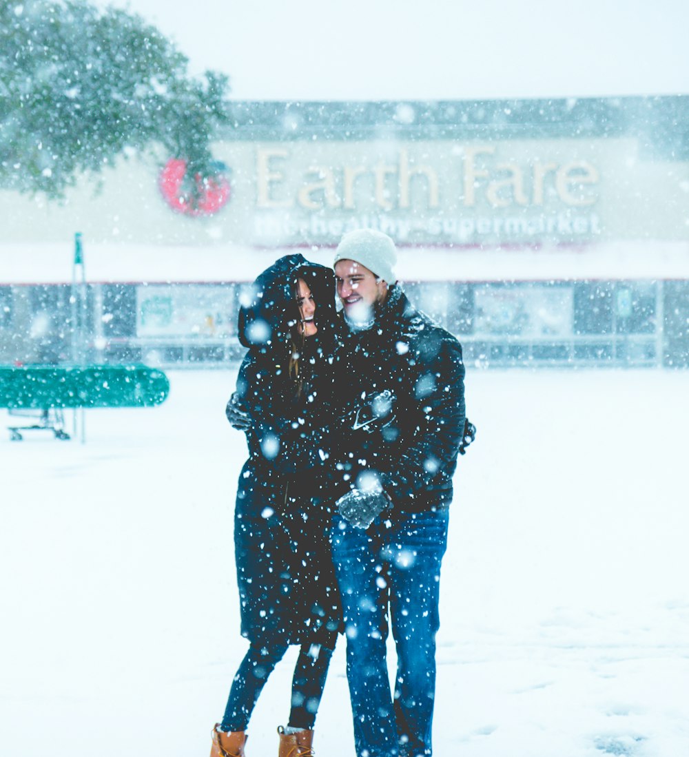 man and woman standing on snowing surface