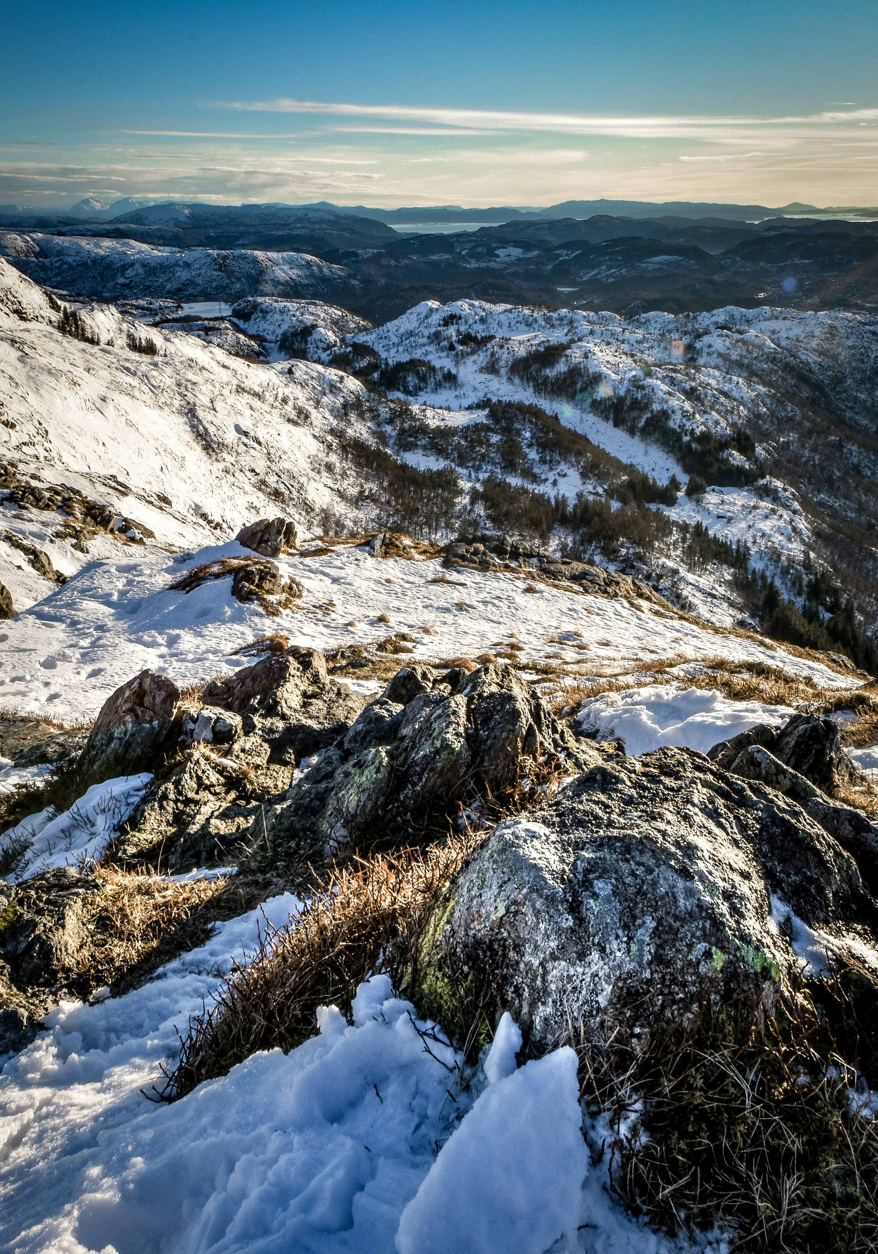 rocky hill covered with snow under blue and white skies