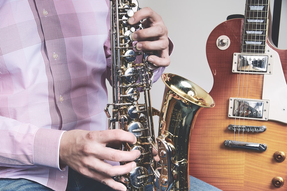 man playing saxophone beside guitar