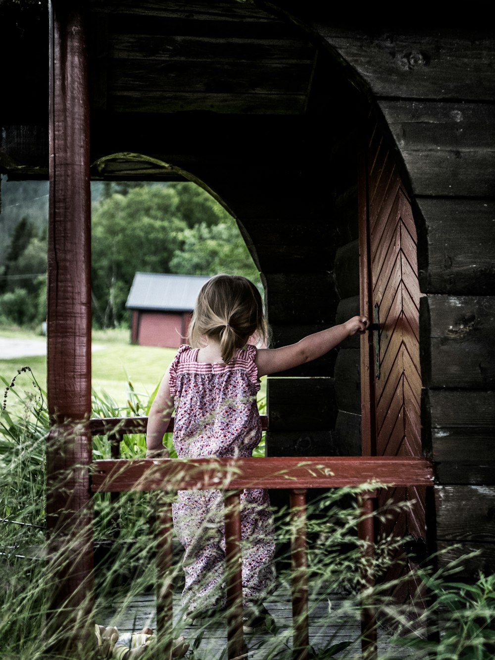 girl in purple dress holding door lever