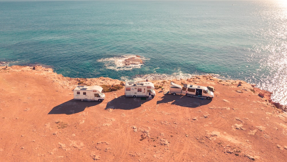 trois parcs de camping-cars blancs près de la mer pendant la journée
