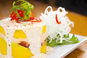 A beautifully plated causa with layers of avocado, chicken, and creamy sauce