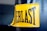 A close-up view of a yellow rectangular label with black stitching that has the word 'EVERLAST' printed in bold black capital letters. The label is attached to a dark-colored textured material, which appears to be part of a punching bag or similar sporting equipment.