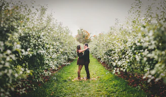 A romantic outdoor engagement photo session with a couple holding hands near a blooming orchard.