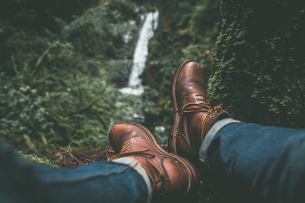 person wearing brown leather boots near green leafed plants