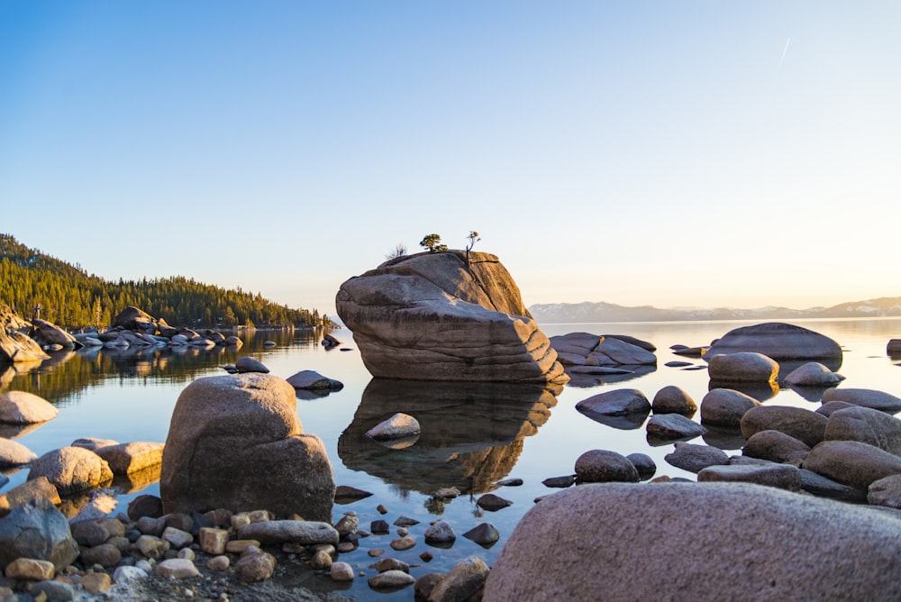 brown rock formation beside calm body of water near mountain at daytime