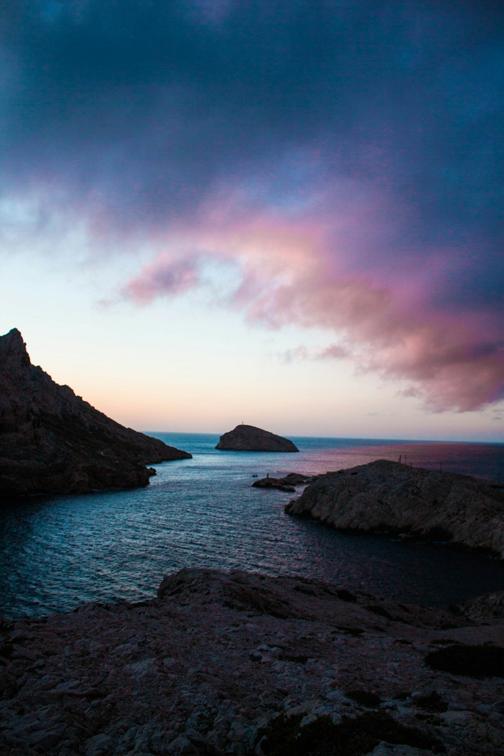 photo of body of water surrounded by rocks