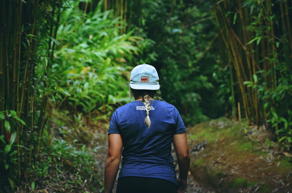 person in blue shirt walking between bamboo trees