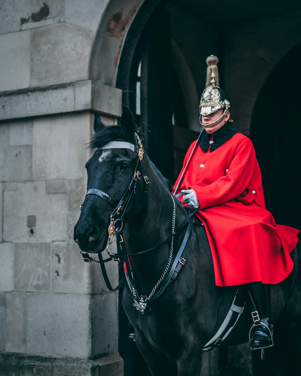 man wearing red coat riding on black horse