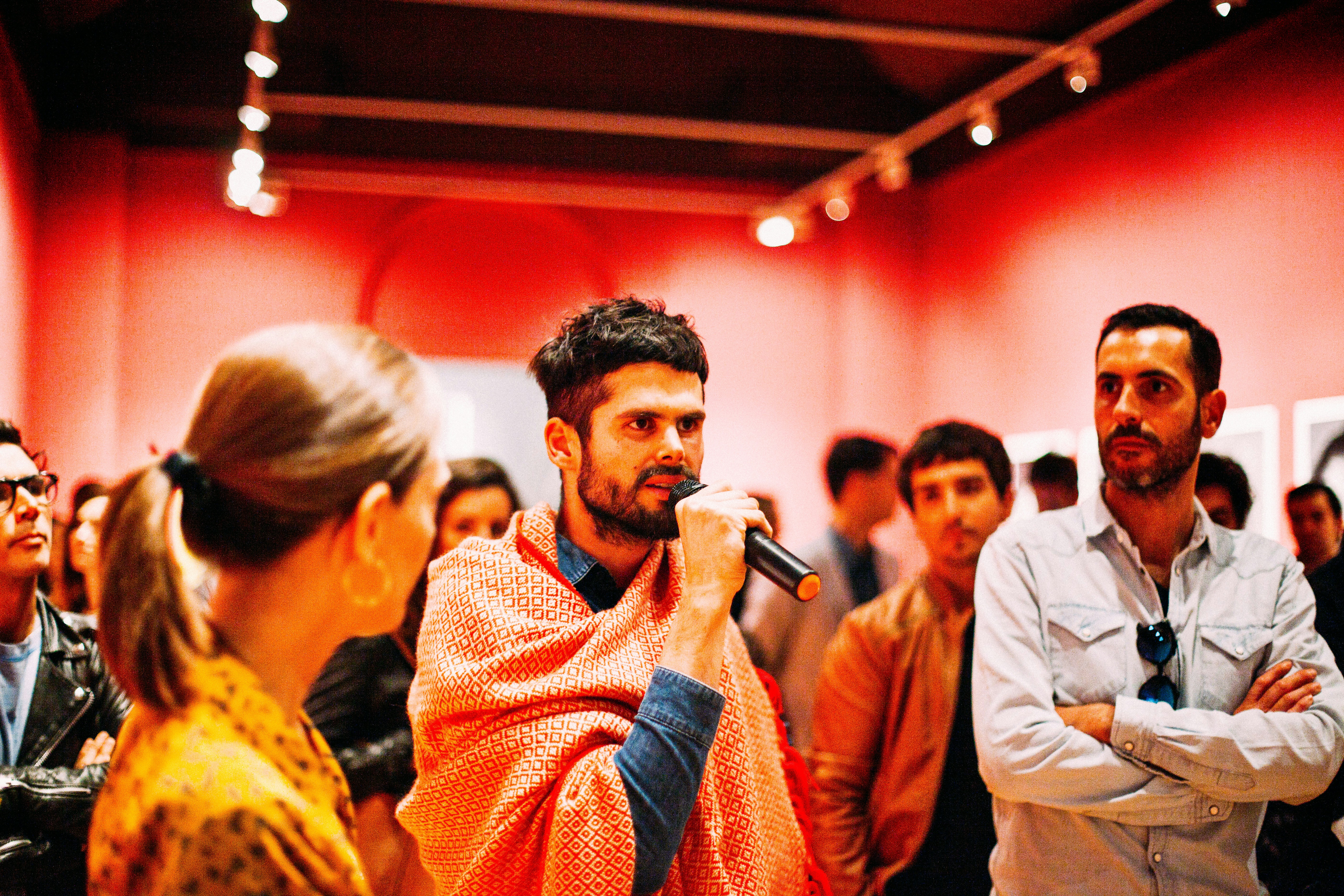 man using microphone speaking surrounded of people inside the room