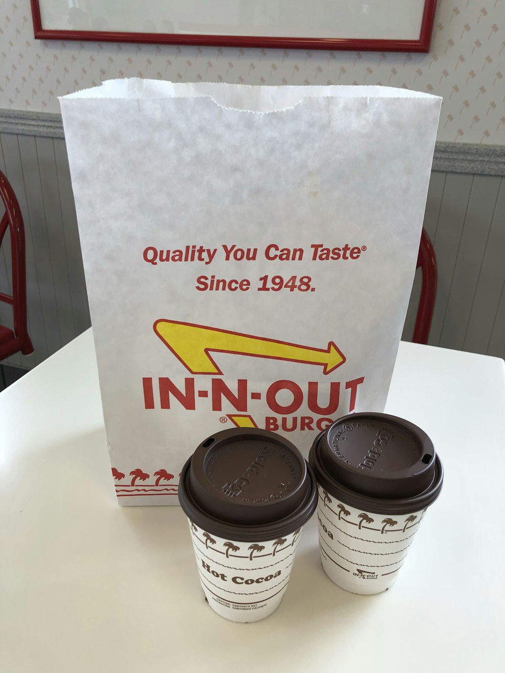 deux tasses de chocolat chaud blanc près d’un sac en papier blanc