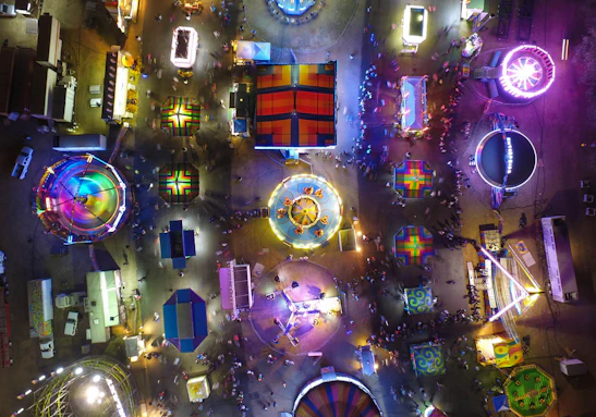 Vibrant evening view of the adventure park with colorful lights and joyful crowds.