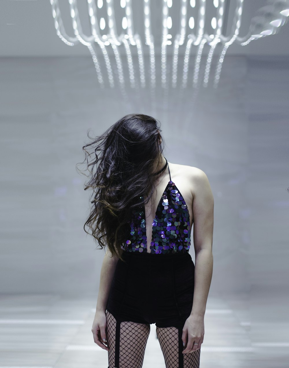 woman standing in middle of white room while bowing her head