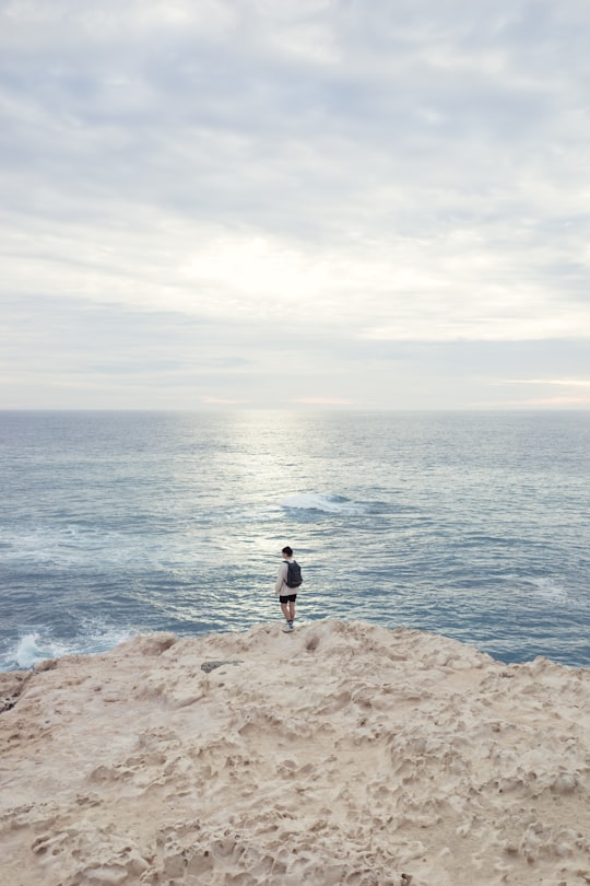 person standing on the edge of the cliff near ocean in Playa de Ajuy Spain