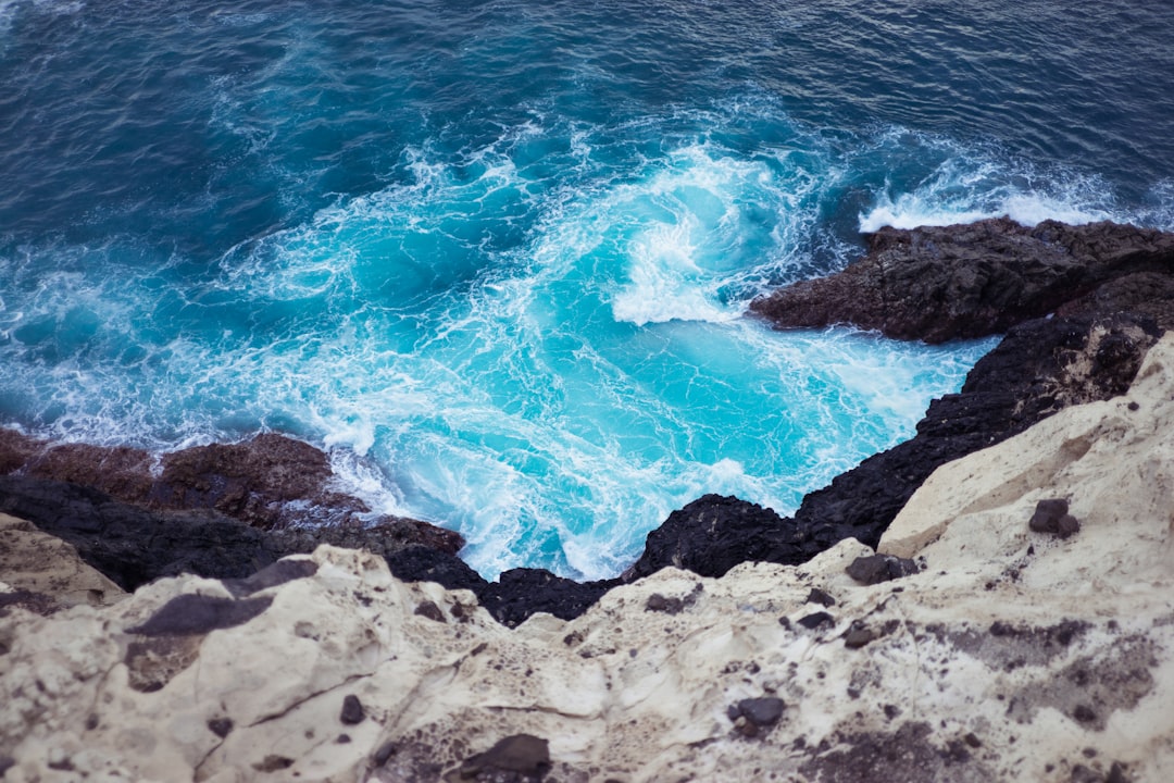 top view photo of ocean waves unto mountain shoreline