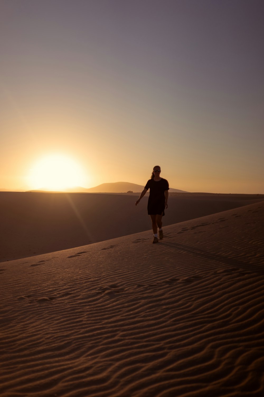 woman walking on desert during sunset
