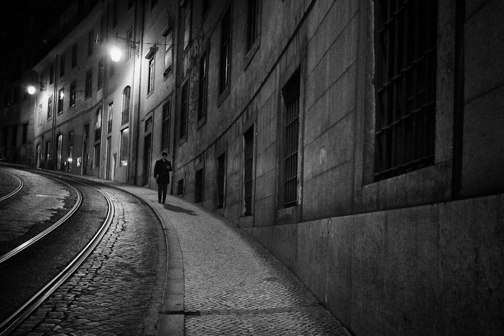 grayscale photo of man walking down the road