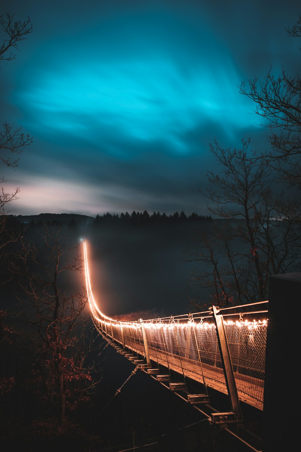 braune Hängebrücke mit Licht in der Nacht