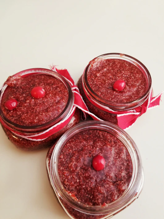 Close-up of homemade strawberry jam jars with rustic labels on a wooden table.