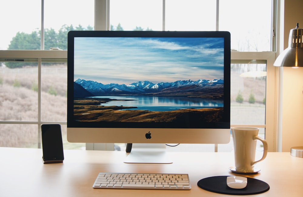 A refurbished Apple Mac on a wooden desk looking out a window in a home ofice