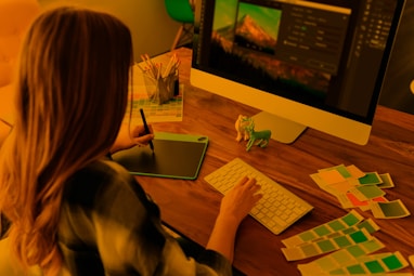 a woman sitting at a desk using a computer exploring colors and creating a children's coloring book