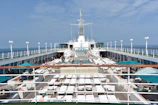 A cruise ship deck with passengers relaxing, showcasing travel essentials like hats and sunglasses.