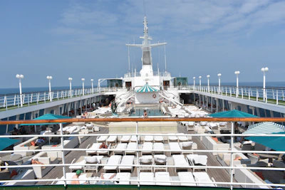 A cruise ship deck with passengers relaxing, showcasing travel essentials like hats and sunglasses.