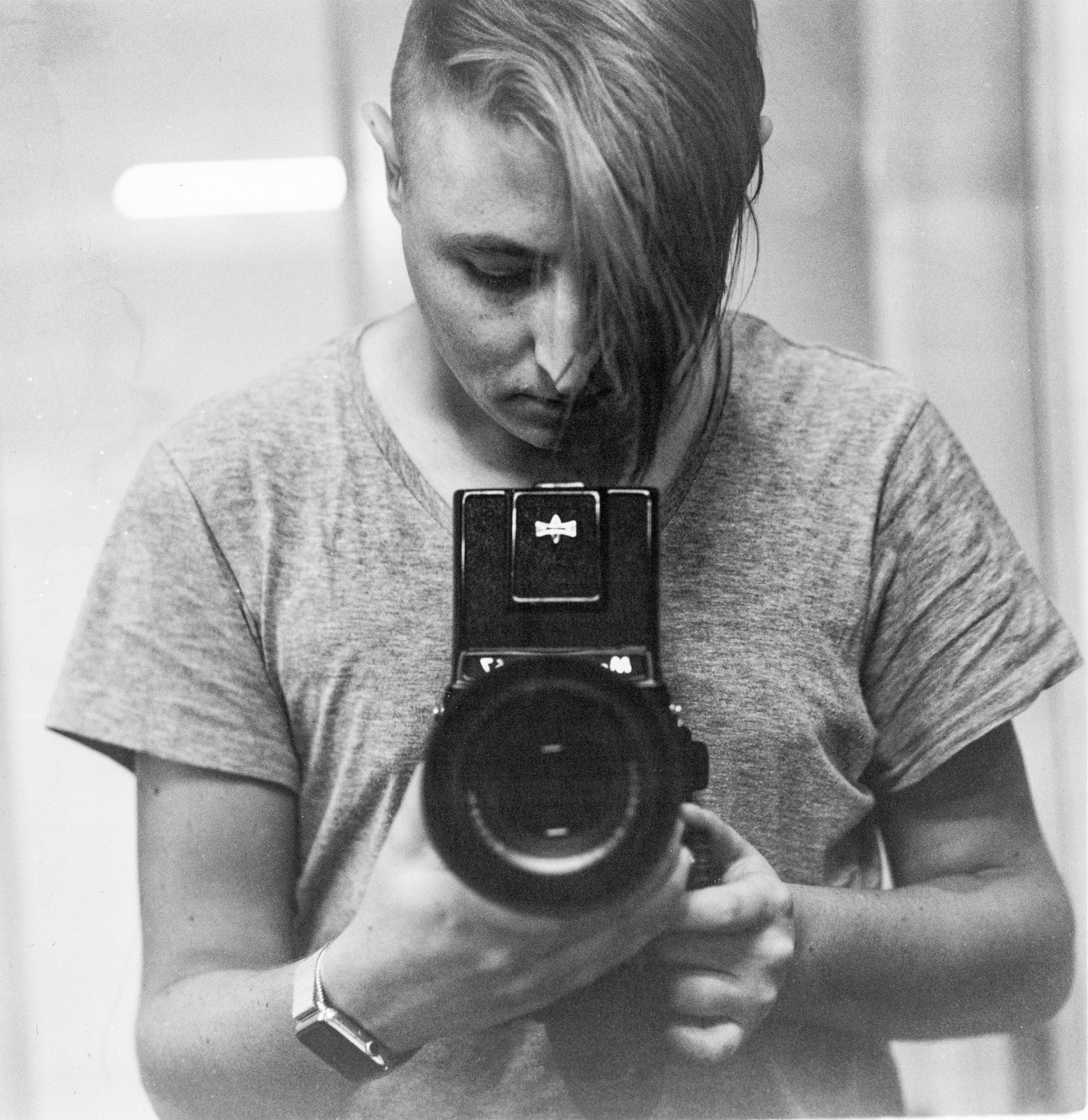A serene black and white portrait of a thoughtful artist holding a vintage camera, symbolizing creativity.