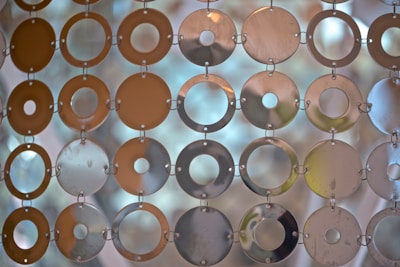 A decorative curtain composed of circular metallic discs interconnected with small rings, allowing light to filter through and casting muted reflections.