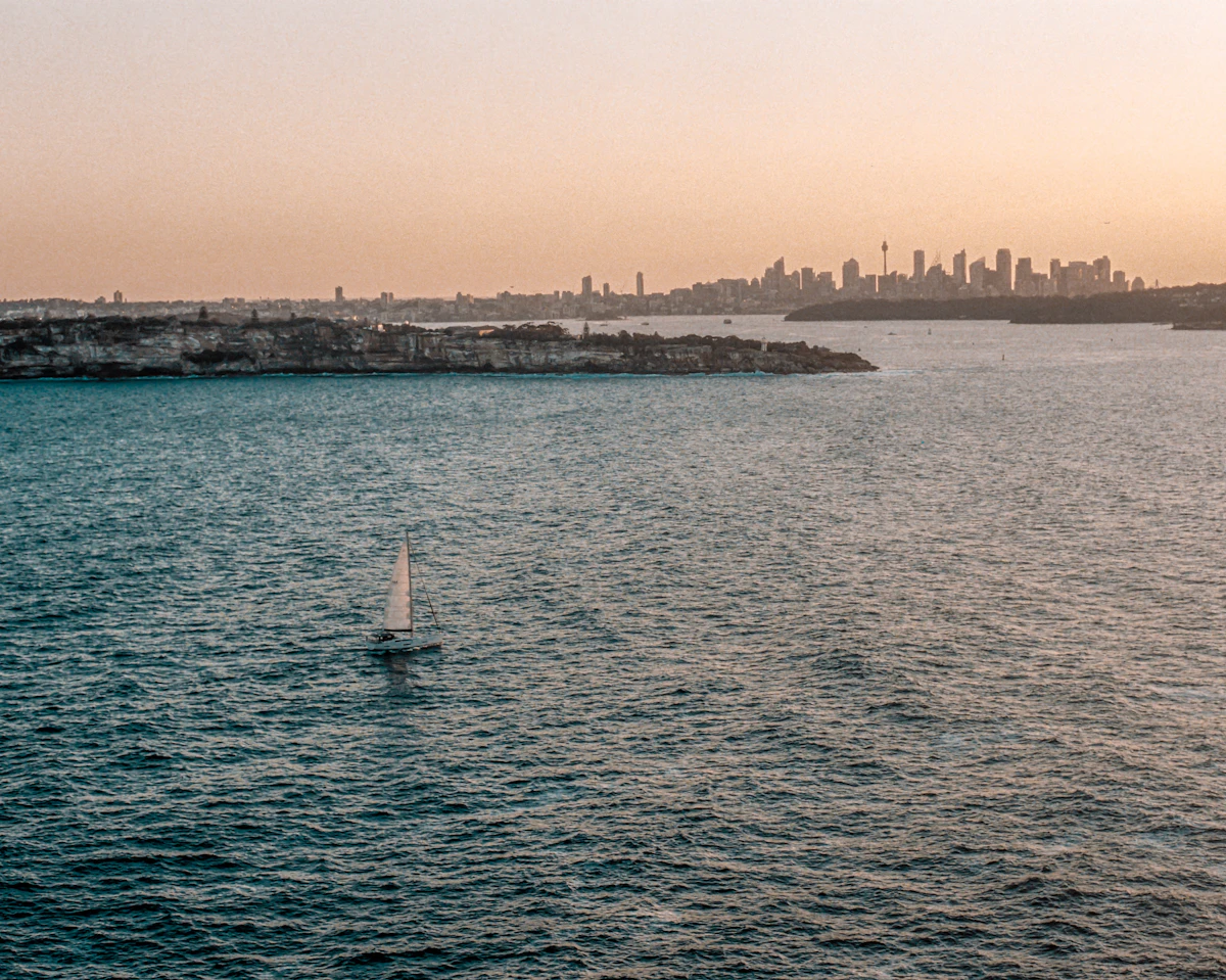 Open Sydney Harbour water with a distant city skyline and rocky headland