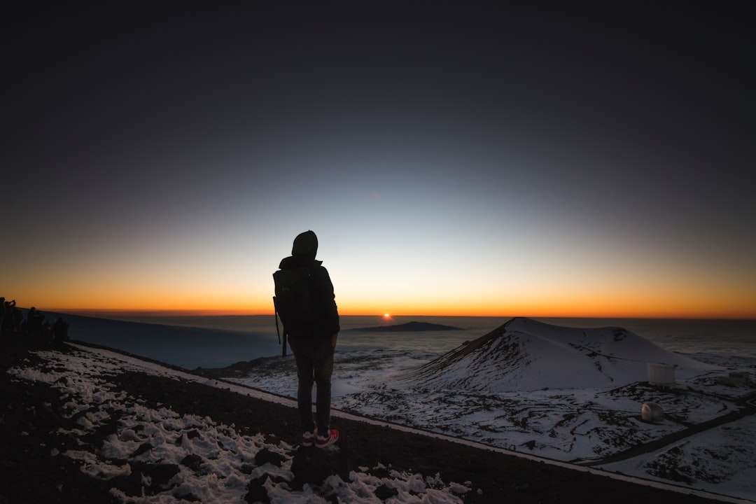person on top of mountain looking at sunset