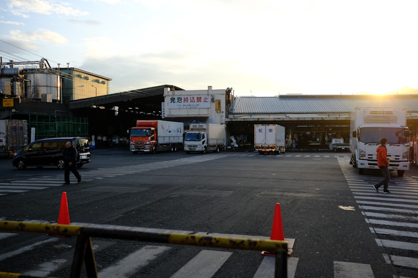 A large Hong Kong freight truck parked outside a modern logistics warehouse at sunset.