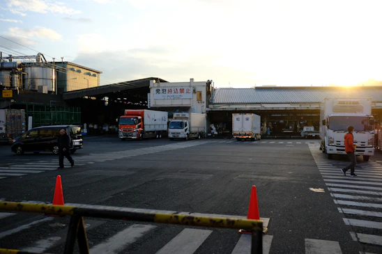 Modern industrial warehouse exterior with dramatic sunset lighting and trucks parked.