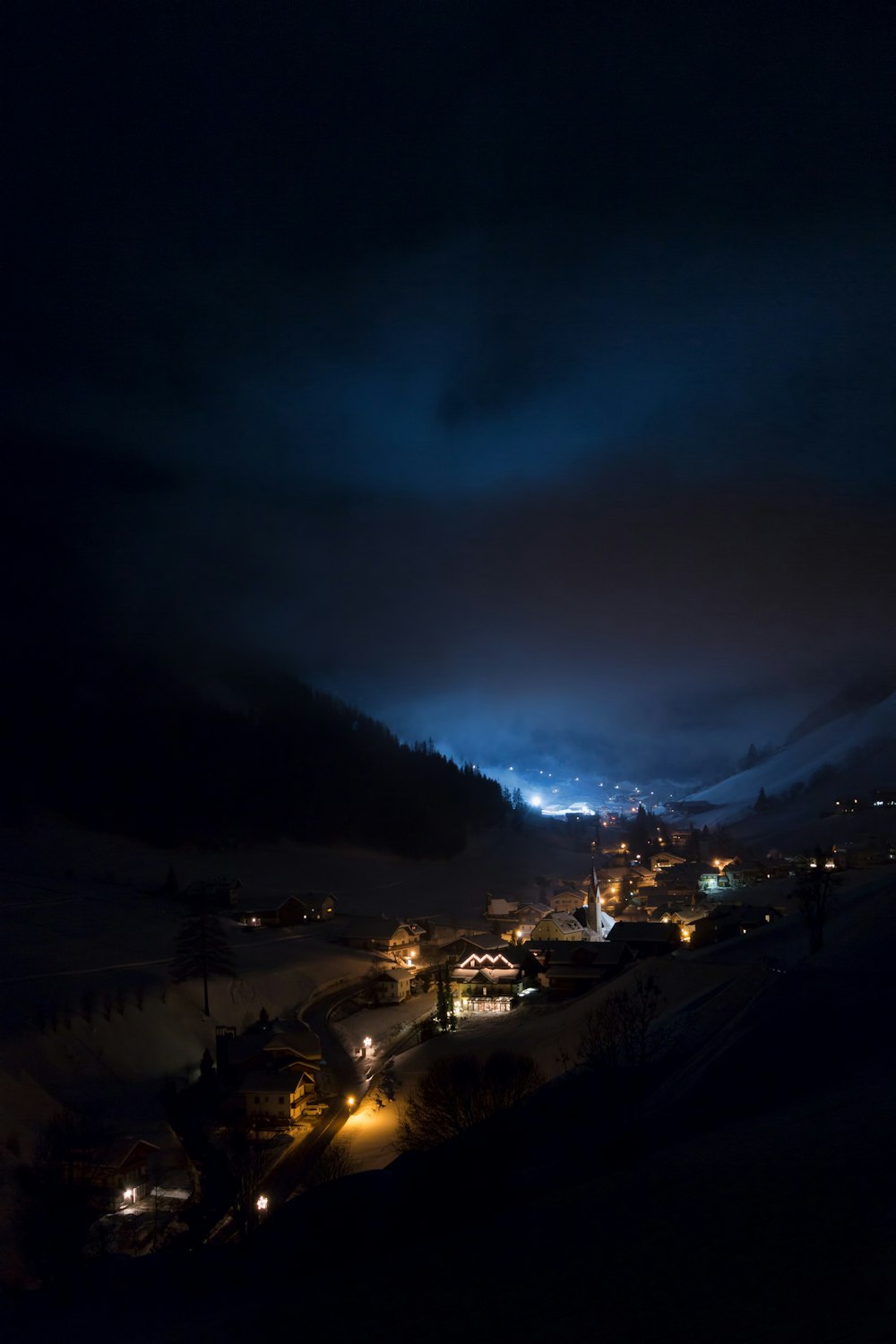 a night time view of a town in the mountains