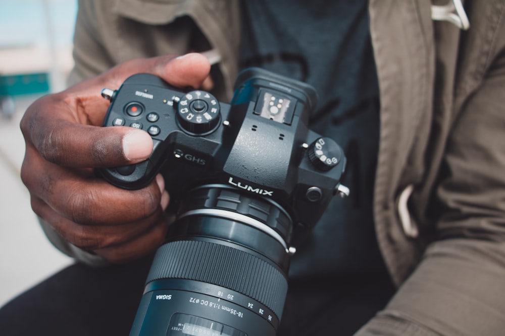 man holding black Lumix DSLR camera