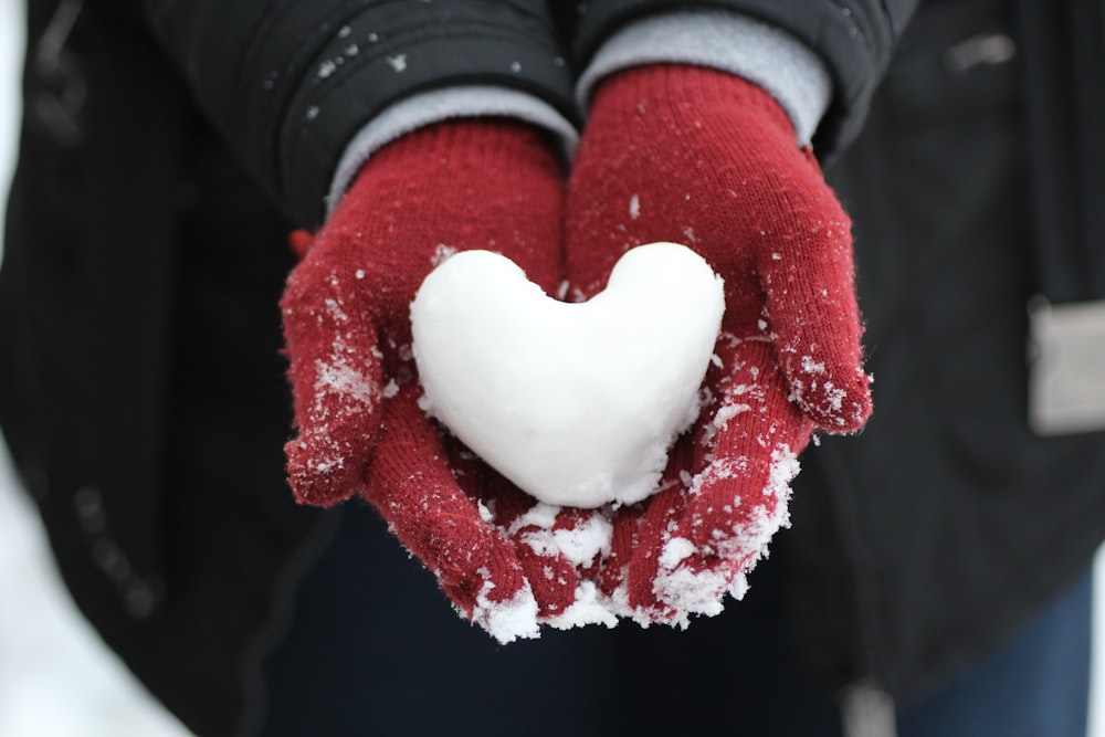 person holding heart-shaped snow