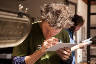 A focused detective examining evidence under a magnifying glass in a dimly lit room.